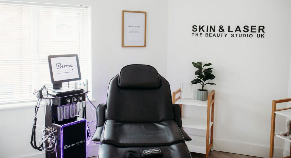 A salon with a black chair, a derma hydra station, and a white wall behind it A salon with a black chair, a derma hydra station, and a white wall behind it