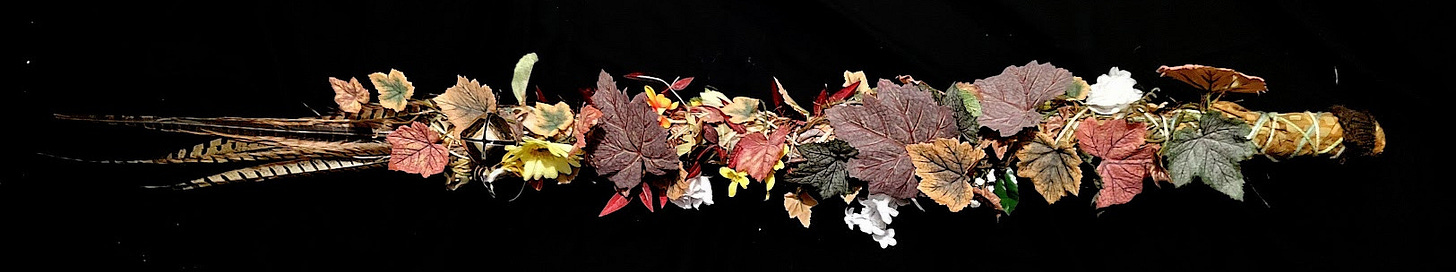 A staff covered in leaves, flowers, bells and feathers.