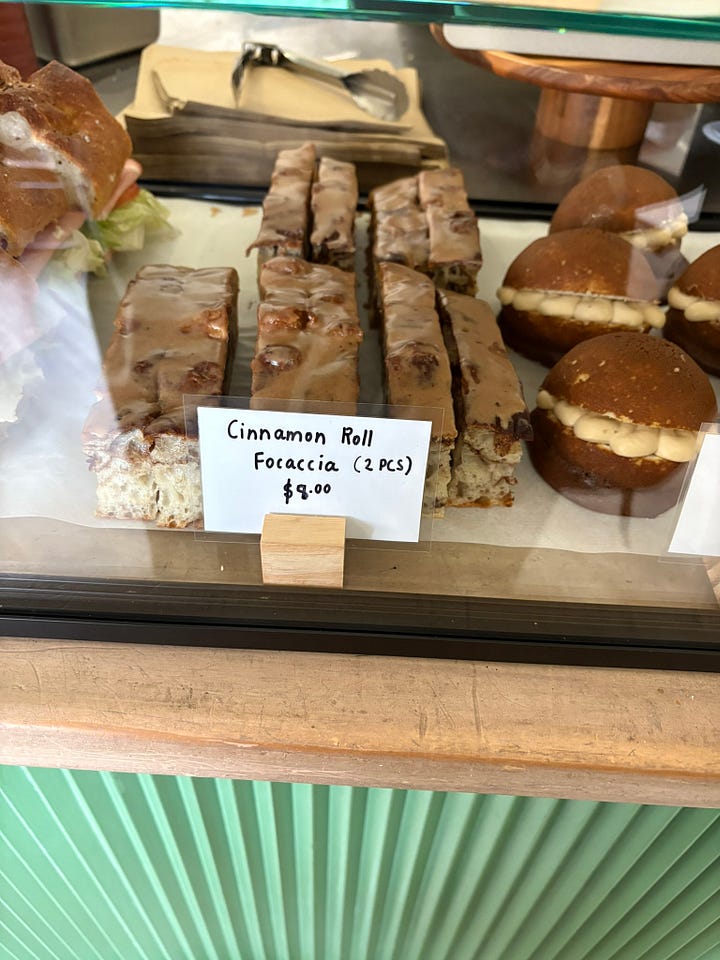 Cinnamon roll focaccia for sale at a cafe and a slab of lemon shortbread with peppermint tea beside a couch