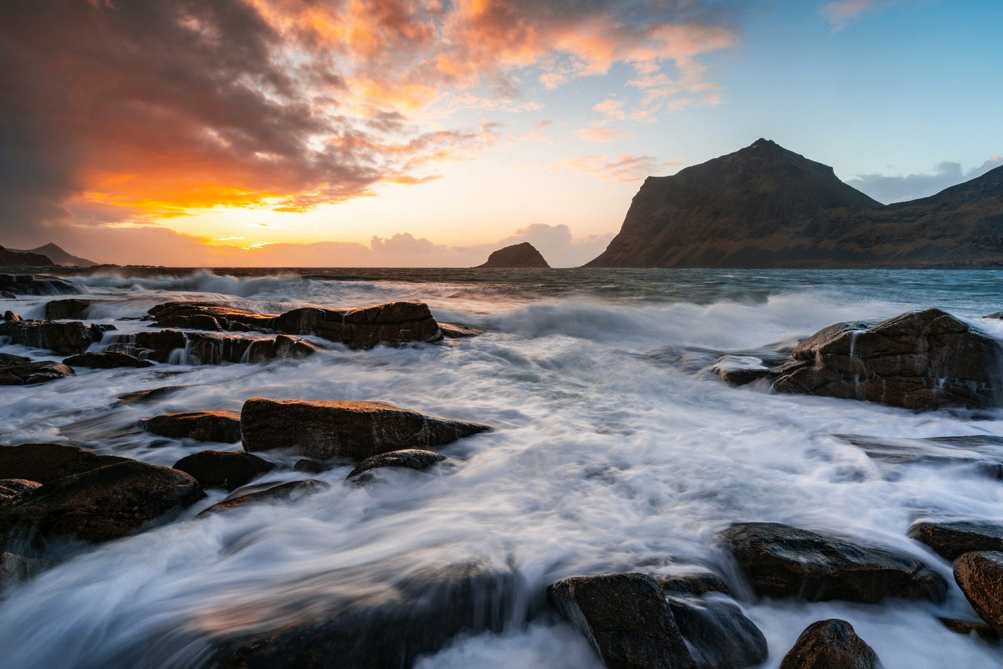 Image of vibrant sunset illuminating ocean waves crashing on a rocky shore in Haukland Beach, Uttakleivveien, Leknes, Norwegen by David Becker on Unsplash.