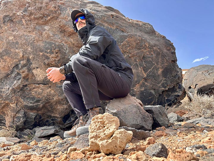 A person sitting alone on a volcanic rock at Montana Blanca, pausing to take in the landscape during a solo hike.