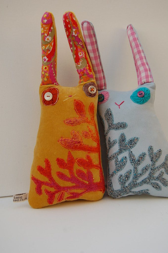 Two fabric rabbits with wool applique and button eyes.