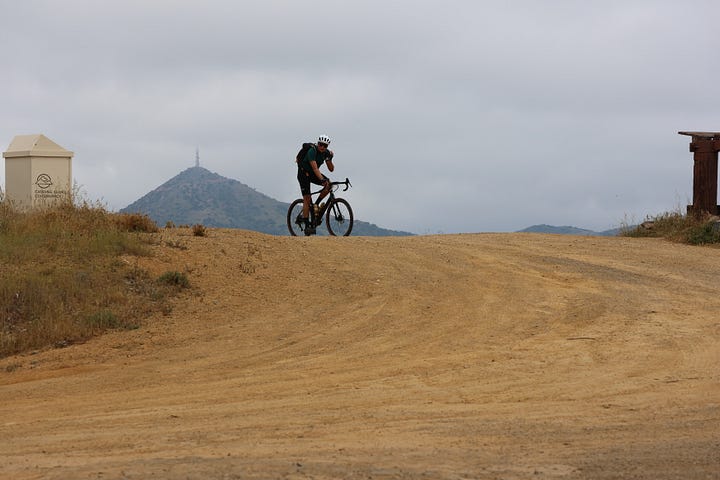 Cyclists climbing up a steep road and reaching a vista point at the top of the climb