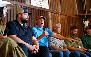 Farmers and speakers sit on a panel at Sovereignty Ranch, with one holding a microphone addressing the audience.