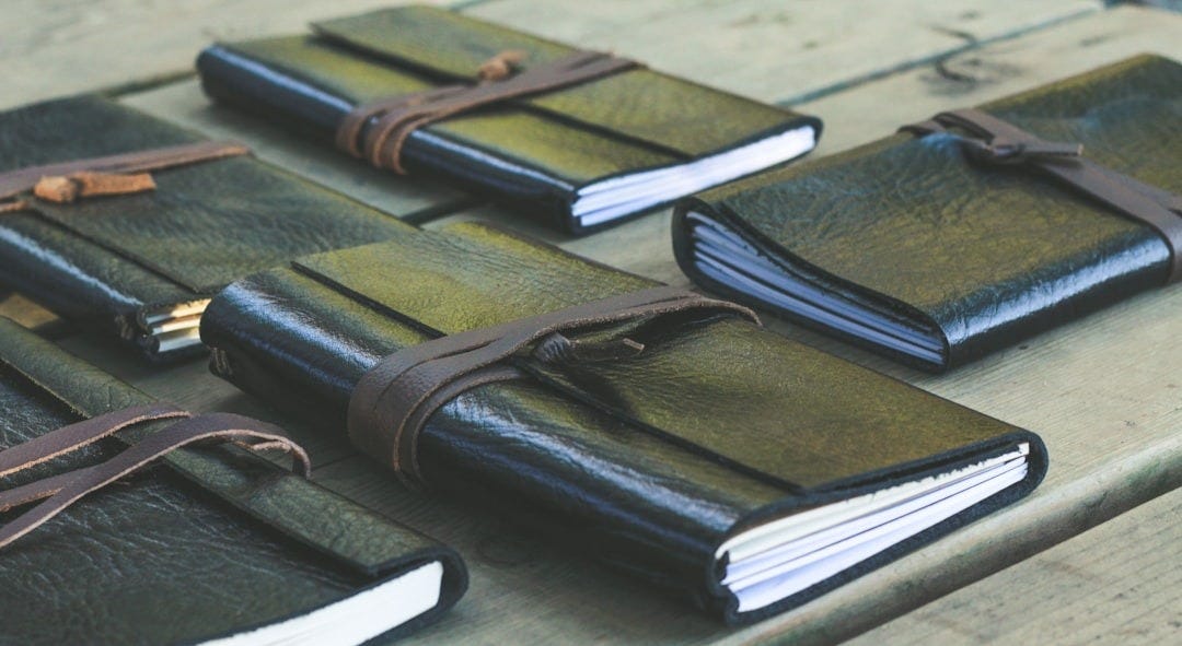 a group of notebooks sitting on top of a wooden table a group of notebooks sitting on top of a wooden table