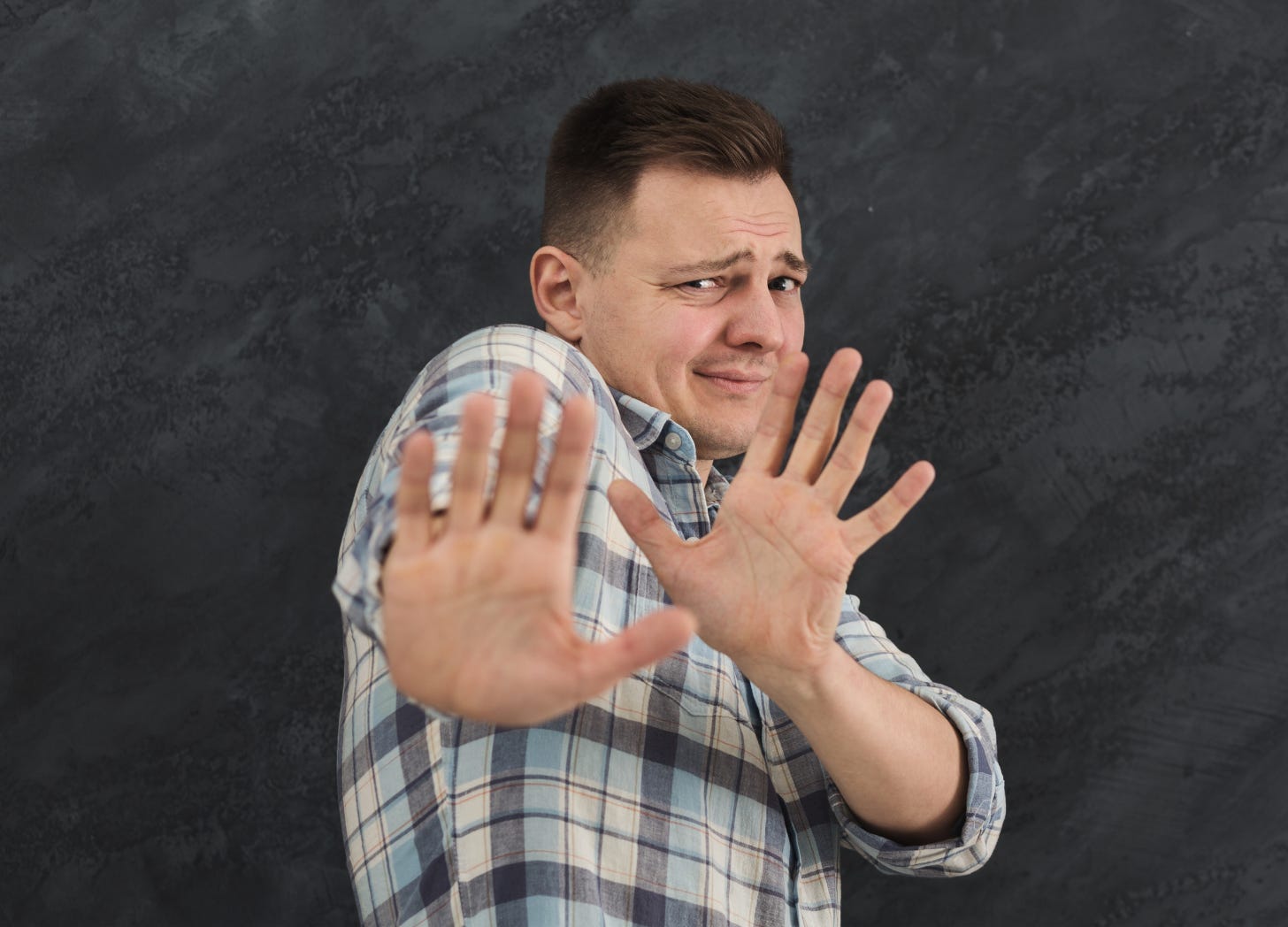 Man expressing aversion by holding up his hands. 