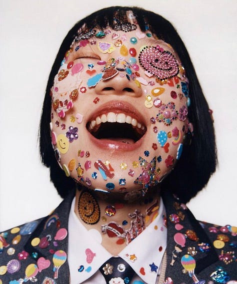 1: A close cropped photograph of a model with dark, bob-length hair against a white background. The model’s eyes are closed, her head tilted up, and her mouth is in an open smile. The model’s face, neck, and visible clothing are covered in an assortment of stickers. 2: A simple illustration in black and white showing a circle that contains smaller half-circles pressed up against one another. The caption reads: “Mosaic of subcultures.” 3: A grainy photograph showing a teenager dressed in baggy jeans and a black t-shirt standing on her bed against two walls filled with posters for bands, rockstars, and other celebrities. One prominent poster is for the band Alice in Chains. 4: A photograph of a pink and white flip phone, surrounded by an assortment of phone charms, including Hello Kitty charms, anime figurines, plush toys, and lip gloss. 5: A young person sits backwards in a chair, turned away from the camera. His face, arms, and back are adorned with star stickers, which shine in the light. 6: A screenshot of a listing on Ebay. The image in the listing shows three closed notebooks laid flat on top of each other. Below the image, a caption describes the listing as “Handwritten Diary, Troubled Teenager, 2000’s.” Below the caption the price read $56. Below the price the listing says 6 bids, Ends in 5 days and 7 hours. 7: The cover of Olivia Rodrigo's debut album Sour. Olivia Rodrigo is standing against a purple backdrop, wearing a fuzzy pale pink tank top and checkered bottoms. She looks at the camera and sticks out her tongue. On her tongue, letters spell out the word “Sour.” Her face is covered in an assortment of stickers. 8: Photograph of a group of four teenage girls posing in front of a white building during an annual U.F.O festival. They are each wearing a matching blue and white striped summer dress, a tiara, a pair of silver alien sunglasses, antennas, and a sash embroidered with the year (2023) and the phrase “Hudson Ambassador” along with their name, written in cursive. 9: A single speaker stands on a stage in front of a crowd almost entirely obscured in darkness. Behind the speaker, a large white screen displays the words: “turn customers into fanatics, products into obsessions, employees into ambassadors, and brands into religions.” The text is all lowercase and in black, but the words fanatics, obsessions, ambassadors, and religions appear in various shades of blue for emphasis.