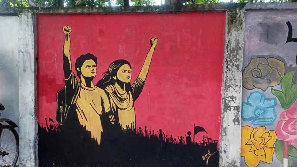 A street mural of two young people raising their fists is painted on a wall.