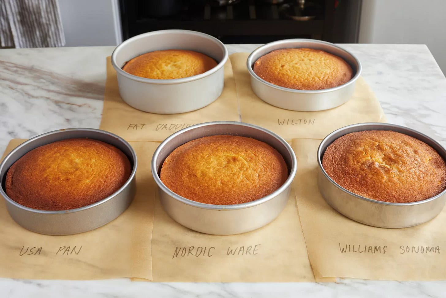 five cake pans with cakes in them on a kitchen countertop