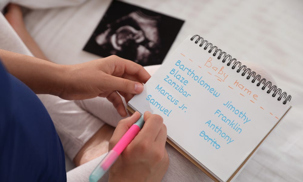 A pregnant woman writing baby names in a notebook with an ultrasound picture in the background