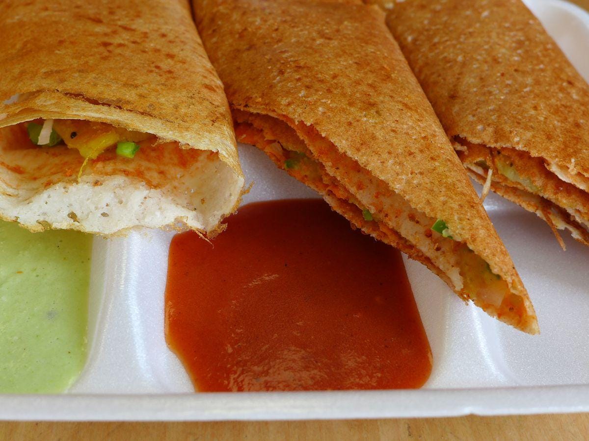 A dosa cut in thirds with two chutneys.
