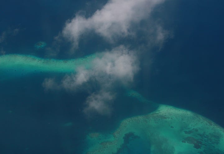 Both images show an aerial view of blue sea where the water is deep and turquoise water where it is shallow, with one image showing a small circle of white which is a sand island