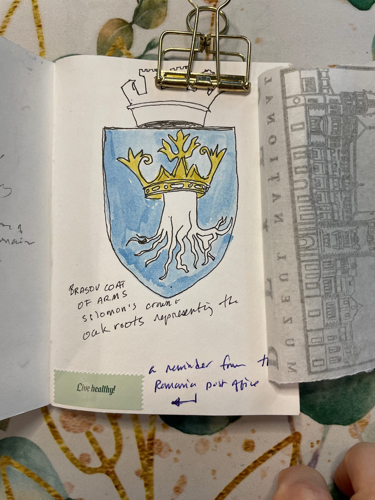 watercolor drawing of coat of arms: light blue background; white tree stump with many roots visible; yellow crown above the tree stump.
