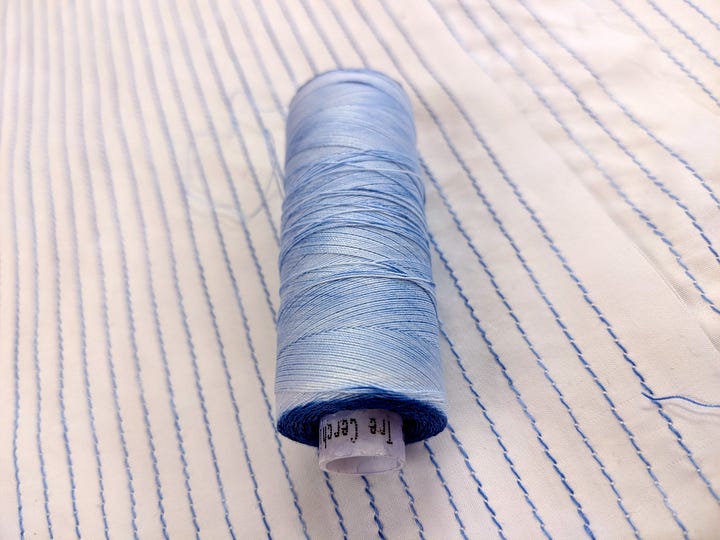 a spool of light blue variegated thread and stitched lines
