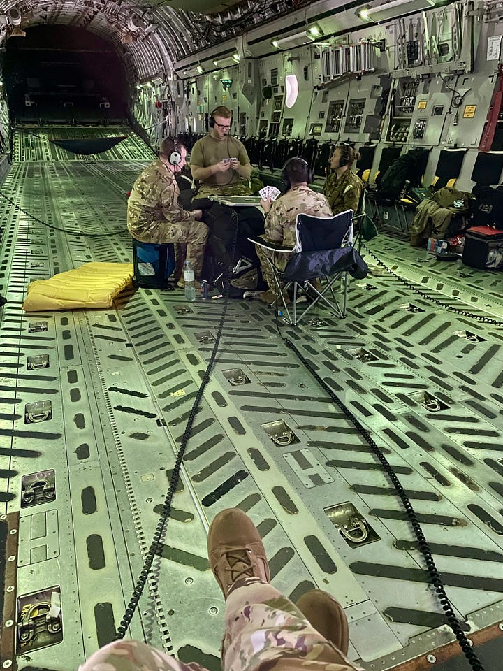 C-17 cargo bay with ammunition and C-17 cargo bay with loadmasters playing cards on a makeshift table