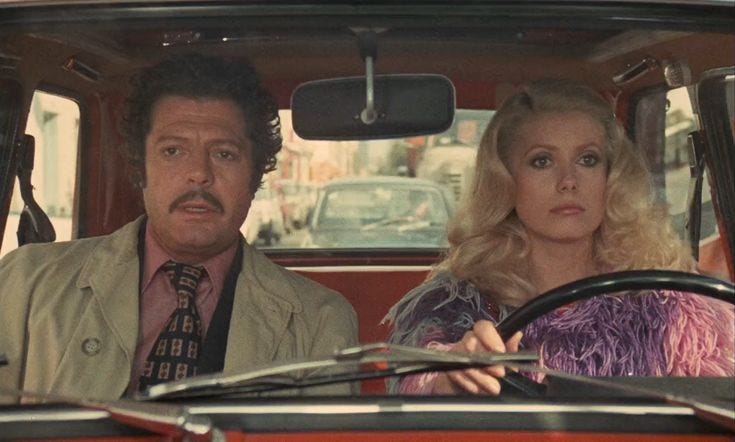 This may contain: a man and woman sitting in the driver's seat of a car, looking at each other