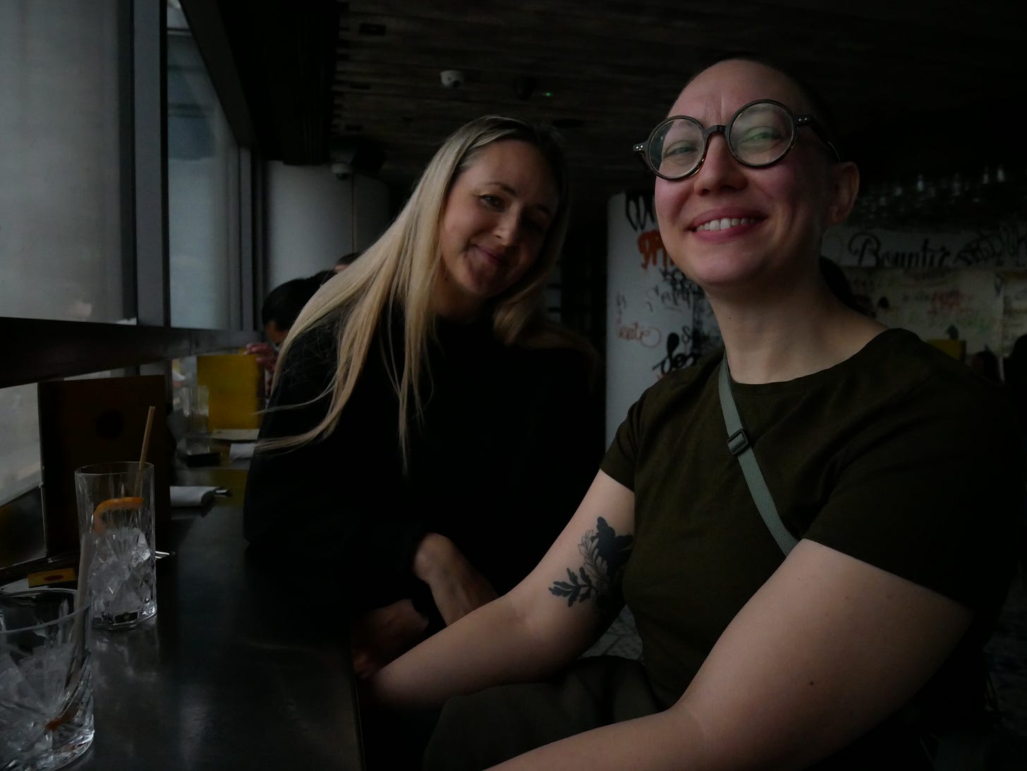 A photograph of Louisa with Mia in a darkly lit bar both with warm grins and eyes to camera. Good times!