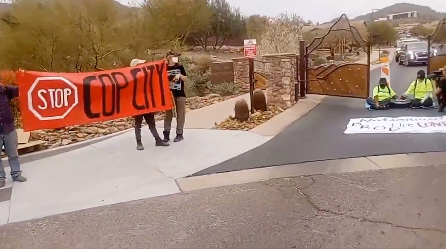 activists holding a stop cop city banner while other activists sit in the street