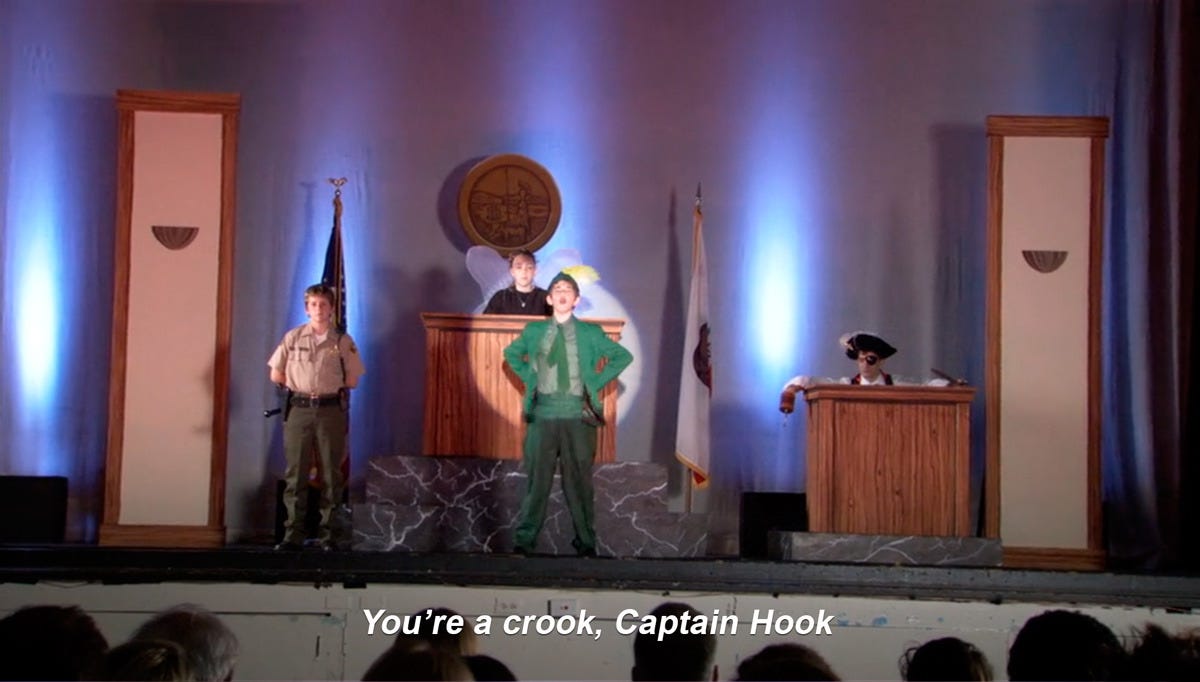 Stage play scene with children dressed as Peter Pan and Captain Hook.