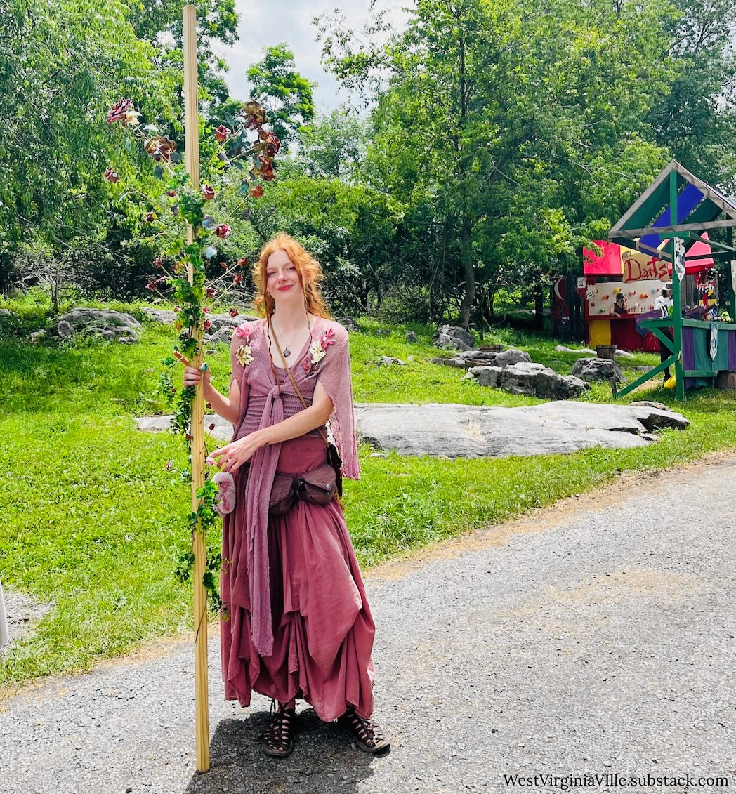 A woman dressed in pale rose-colored Medieval garb selling metallic roses at the 2025 West Virginia Renaissance Festival in Lewisburg, West Virginia A woman dressed in pale rose-colored Medieval garb selling metallic roses at the 2025 West Virginia Renaissance Festival in Lewisburg, West Virginia