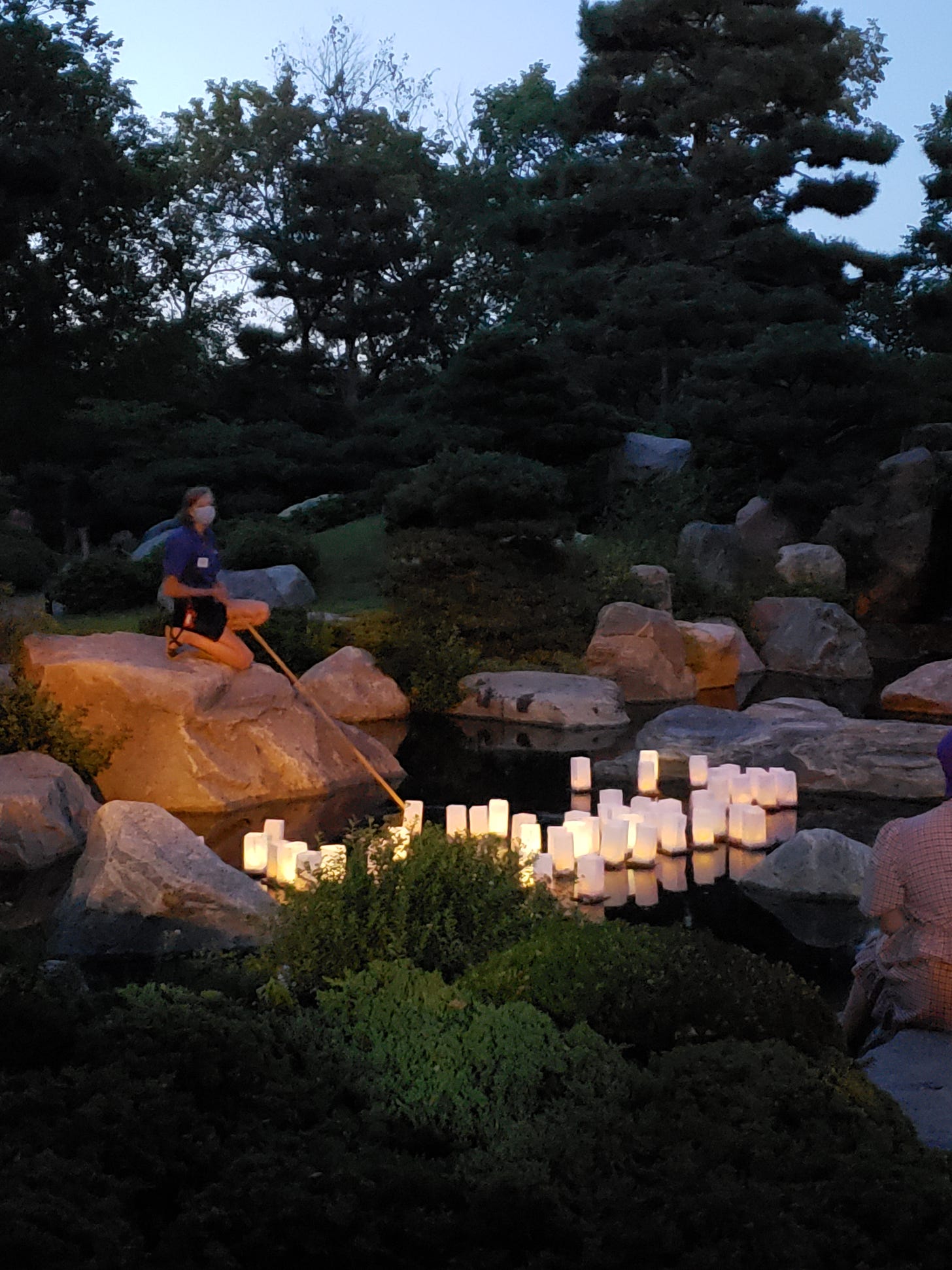 A worker uses a long stick to keep the floating lanterns from bunching up.