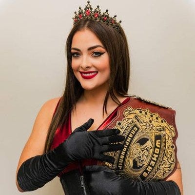 Debbie Keitel holding championship belt and wearing a crown