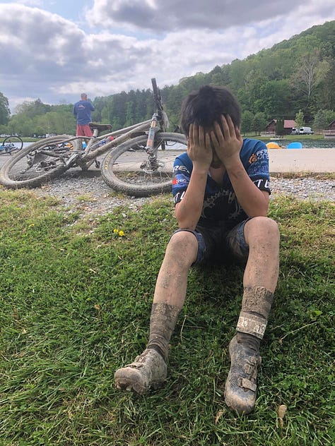 Alex Liu, the youngest person ever to finish the Mohican MTB 100 race, holds his face in his hands during the Mohican Mountain Bike 100 race.