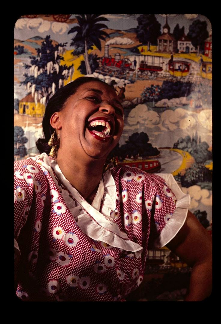 This may contain: a woman laughing while sitting in front of a wall