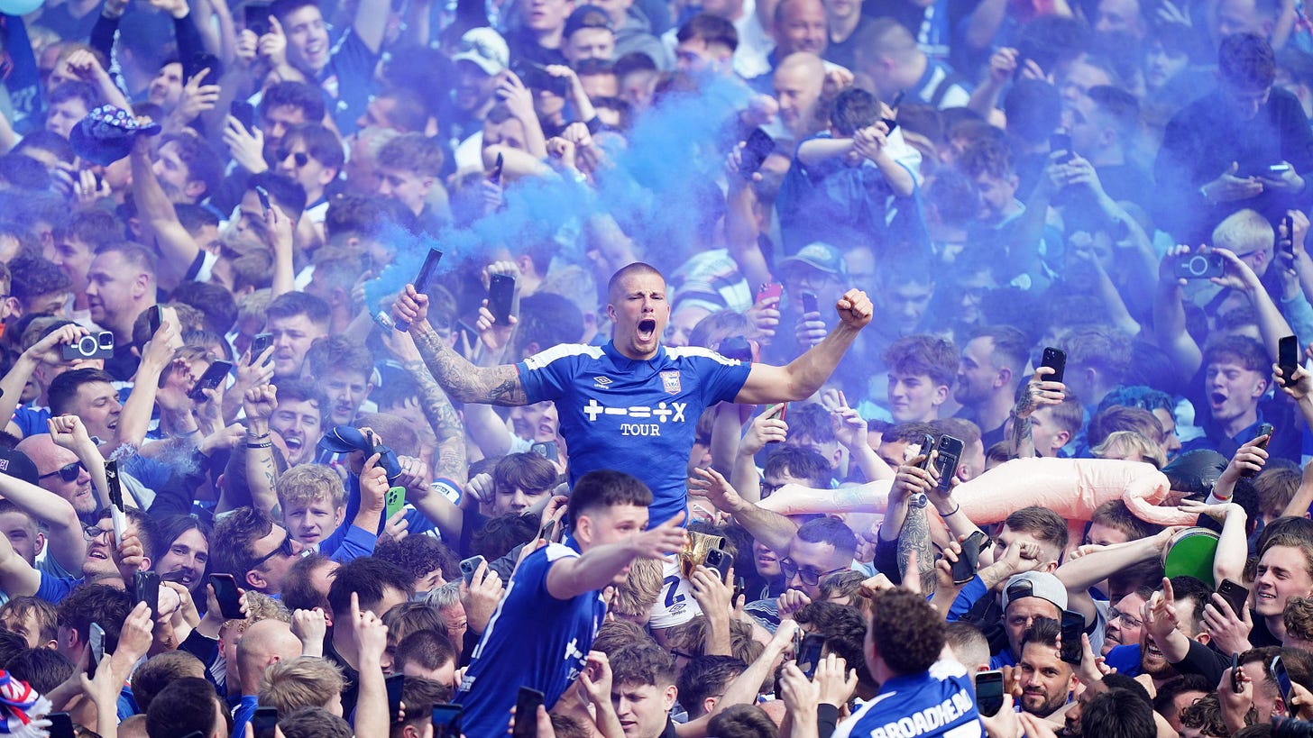 Pitch invasion after 2024 promotion, Harry Clarke is held aloft with a blue flare