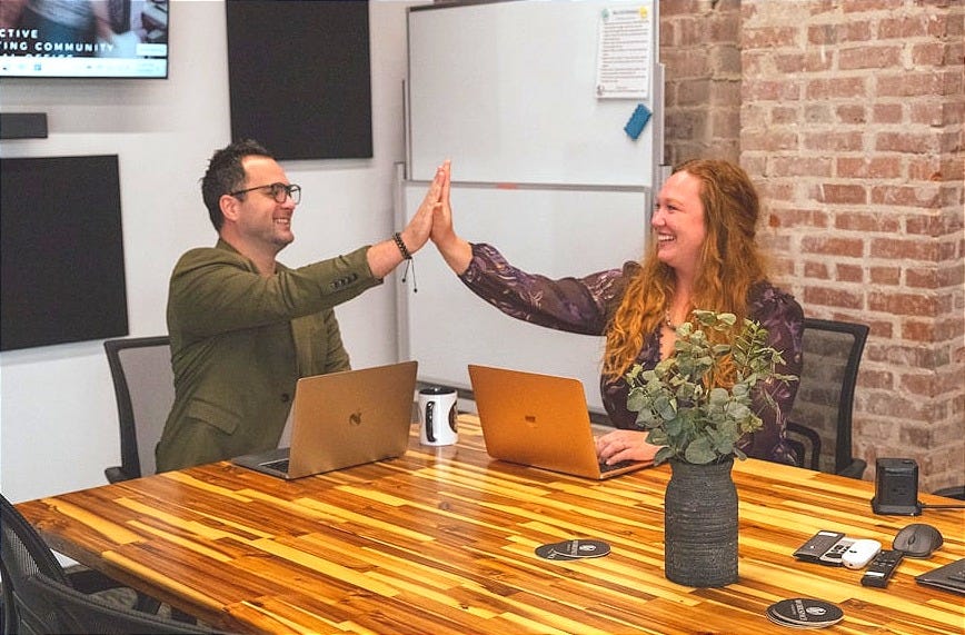 Two people high-fiving in a meeting room.