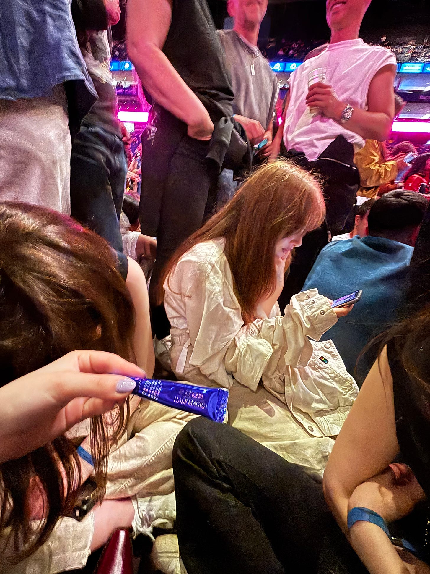 A candid photo from the O2 arena during the Rosalía LUX Tour, showing Gia holding the Half Magic lip gloss amidst the concert crowd.