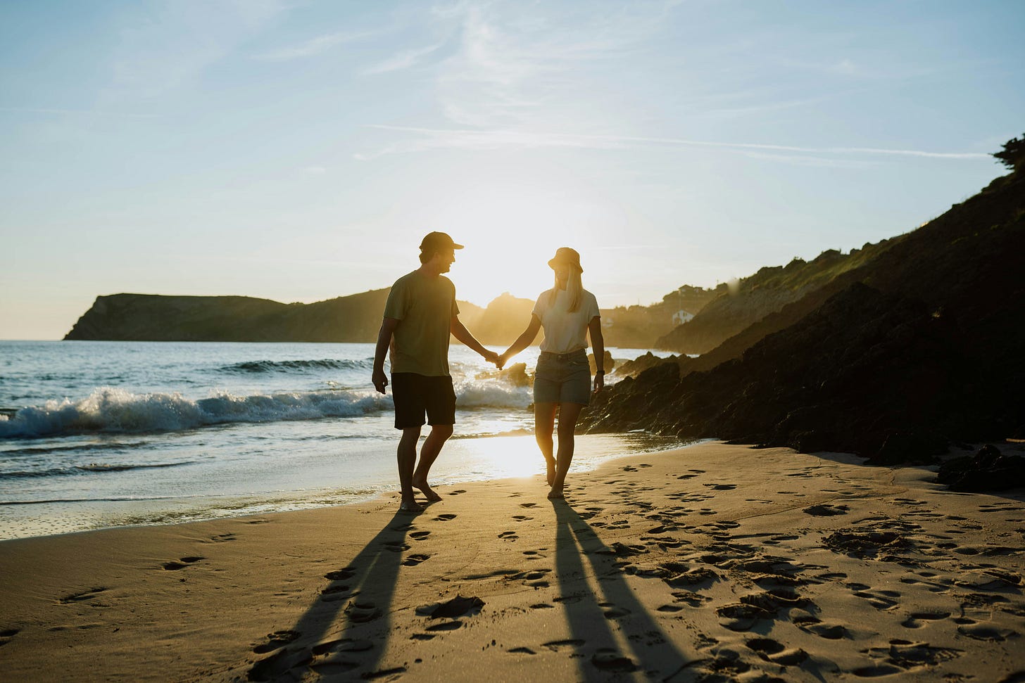 a happy couple holding hands on a beach