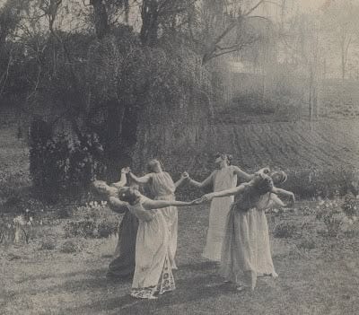 This may contain: four women in long dresses are holding hands