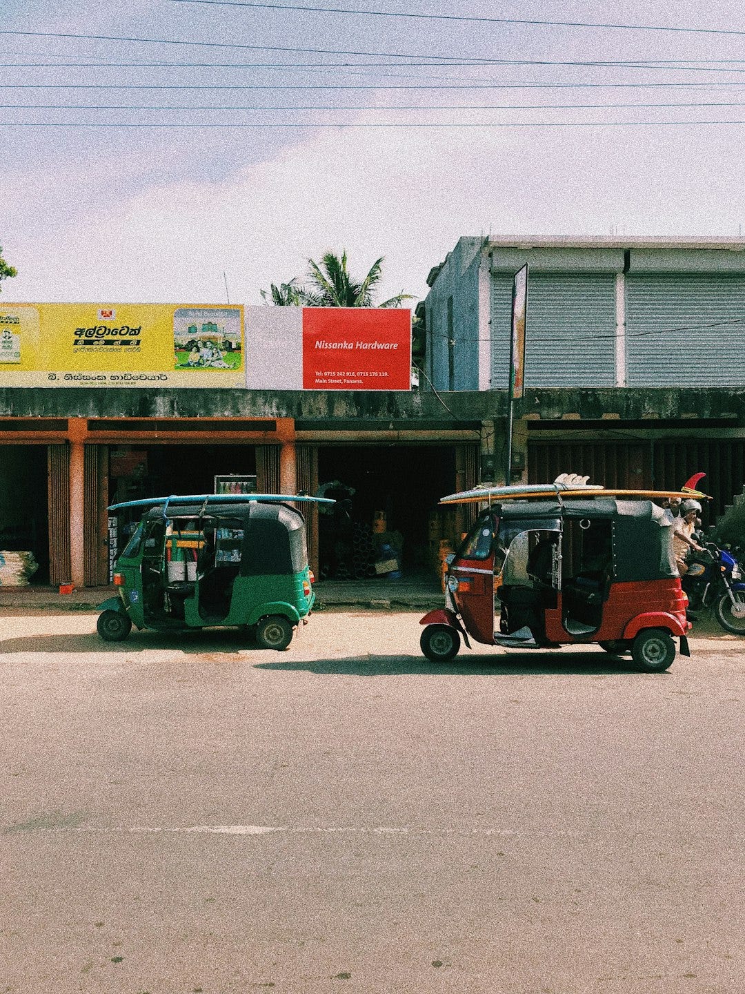 red and black auto rickshaw parked beside white building red and black auto rickshaw parked beside white building
