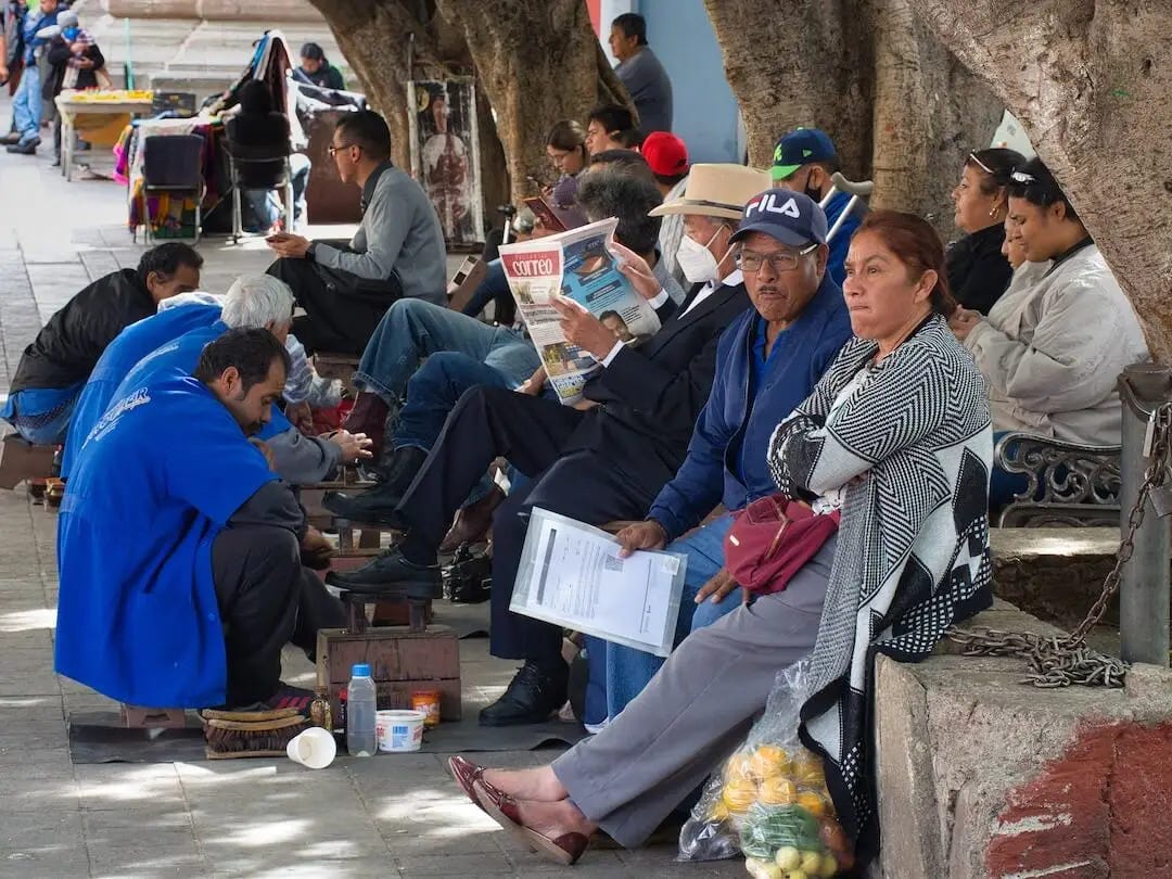 Men in blue tops shine shoes for a row of customers