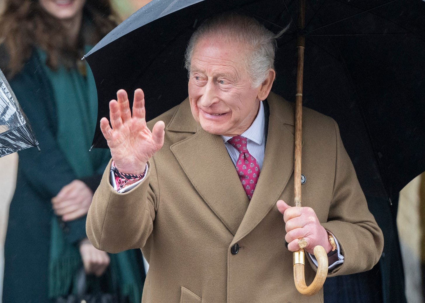 King Charles holding an umbrella and waving