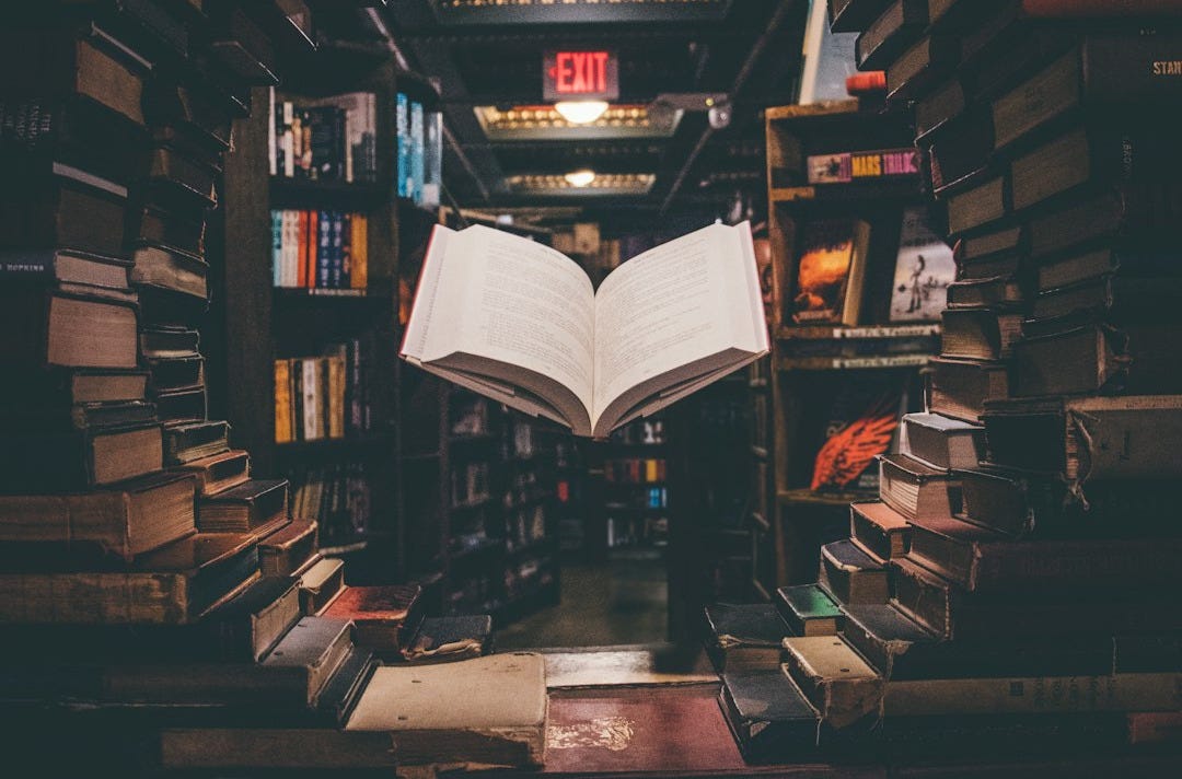 view of floating open book from stacked books in library