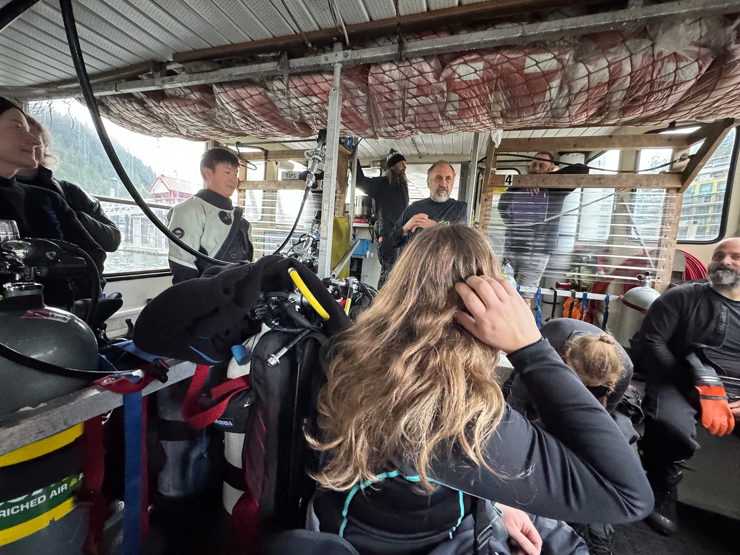 group photo with divers looking a salty looking bearded man who is the captain of the dive boat.