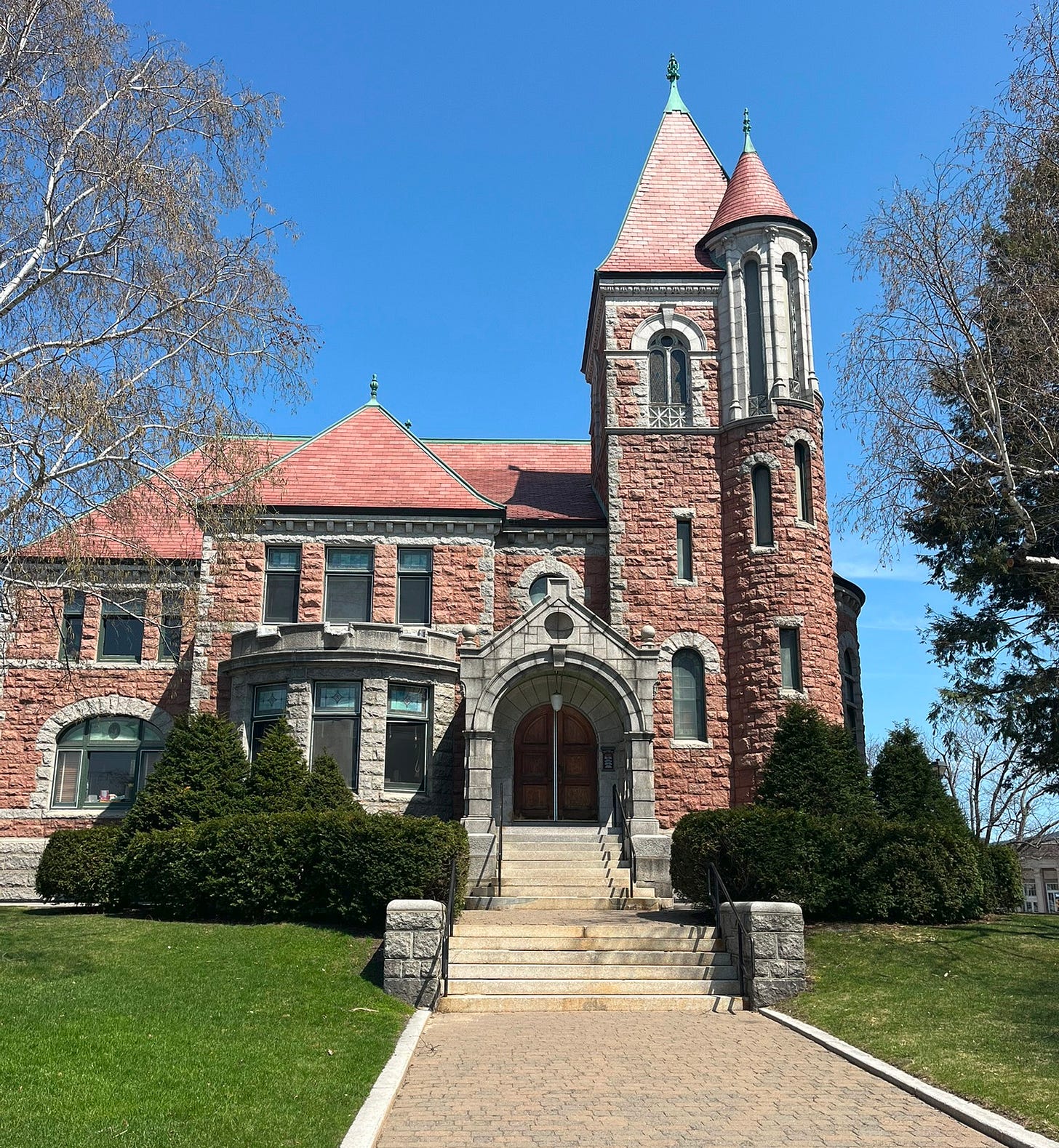 a castle-like library under a bright blue sky flanked by trees