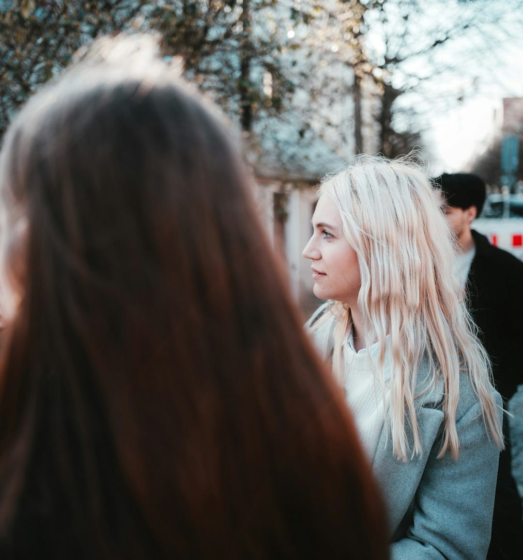 a woman with long blonde hair standing in front of a group of people