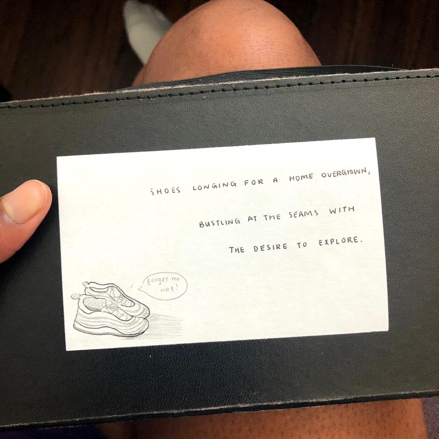 an unlined index card with a drawing of shoes in the bottom left corner that have a speech bubble saying "forget me not!" The top right corner of the card has "Shoes longing for a home overgrown, bustling at the seams with the desire to explore." written in my handwriting.