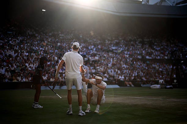 Italy's Jannik Sinner helps up Germany's Alexander Zverev after her fell during their men's singles final tennis match on the fourteenth day of the...