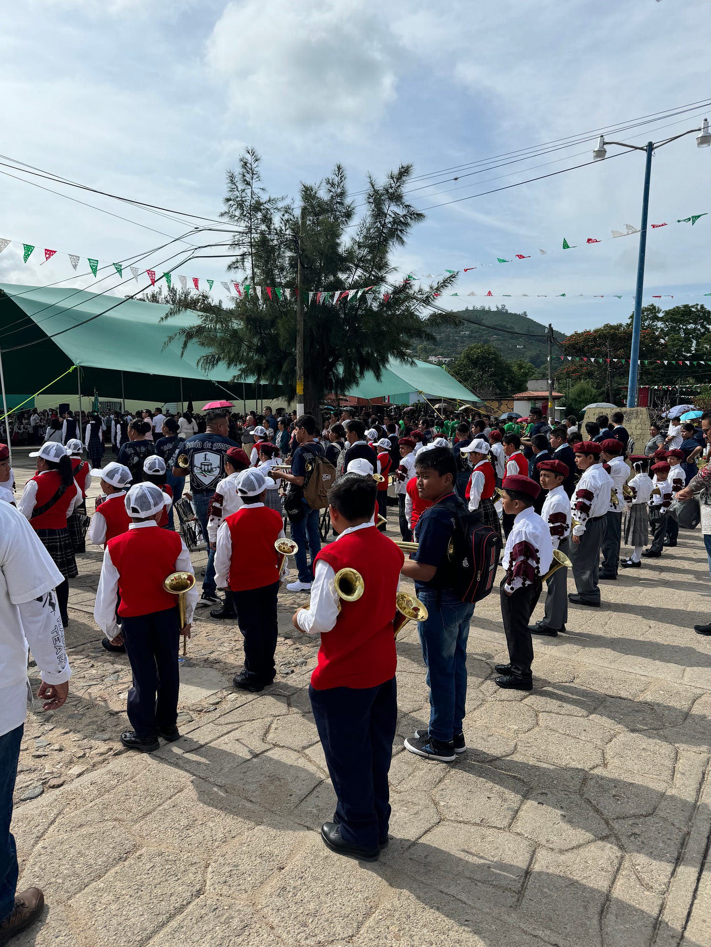 Children wearing military-like school uniforms lined up with brass instruments.