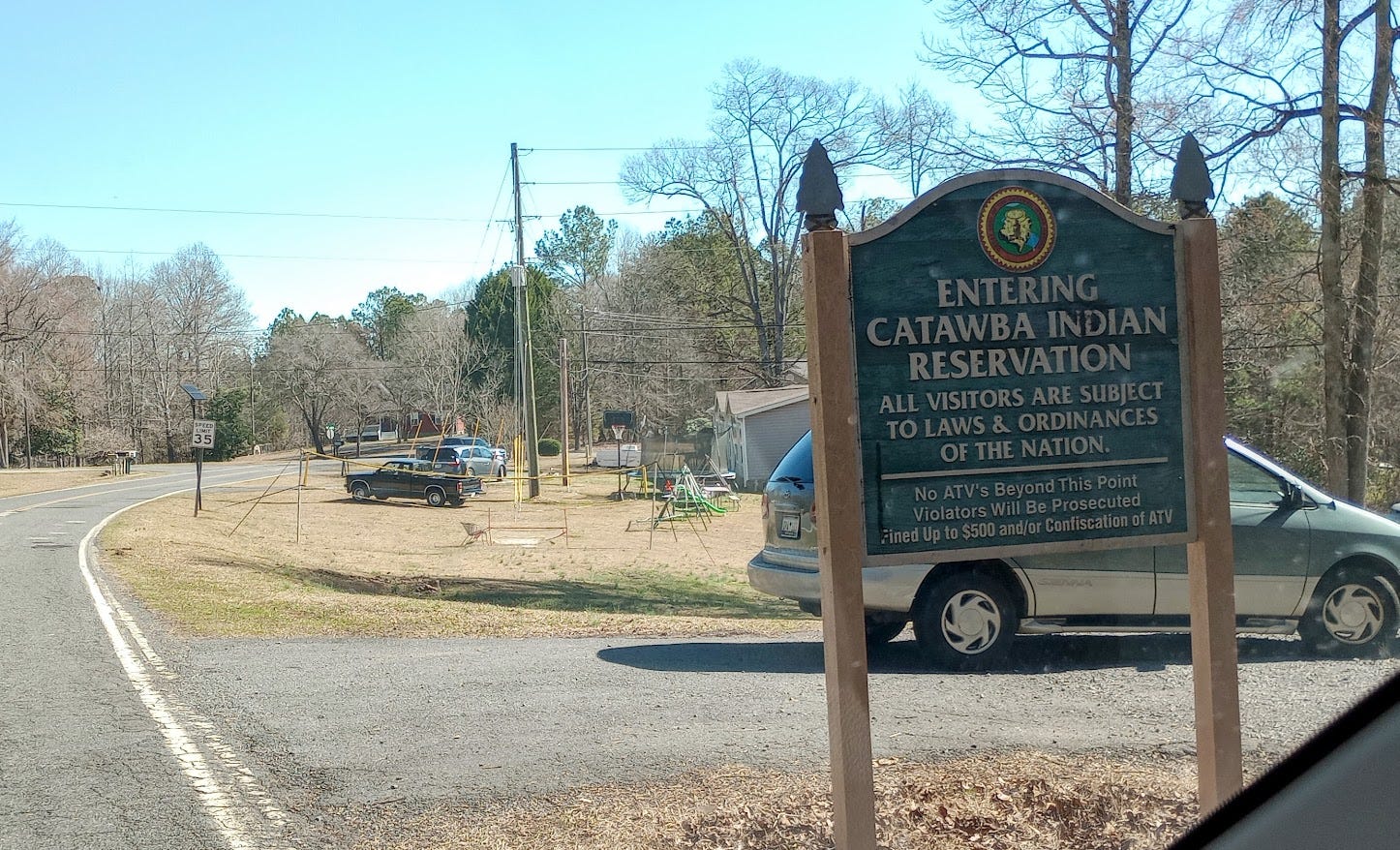 Sign that indicates we're entering the Catawba Reservation, road, cars, houses