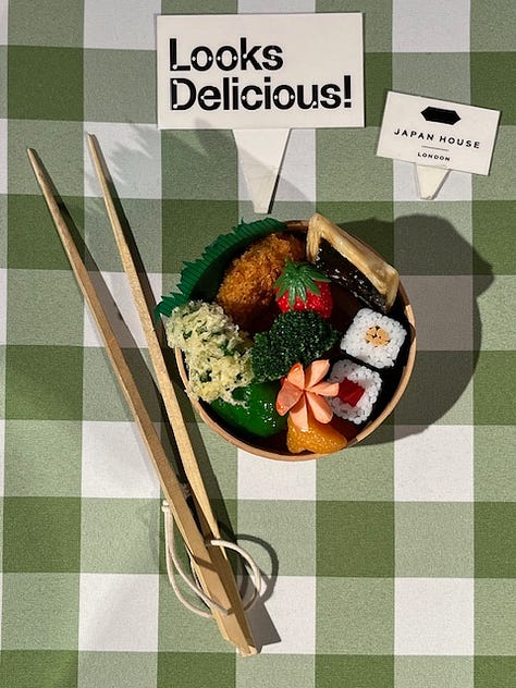 Three examples of colourful, Japanese replica dishes including a bento box and two desserts with fruit, cherries and cream