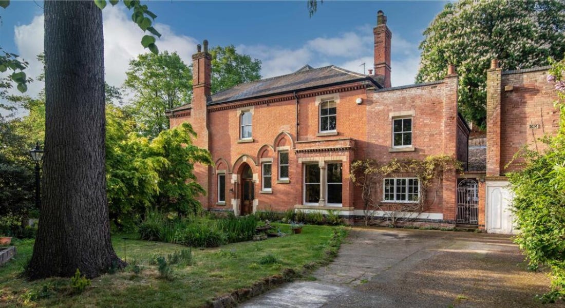 A large brick Victorian house with a tall tree and grass in front of it A large brick Victorian house with a tall tree and grass in front of it