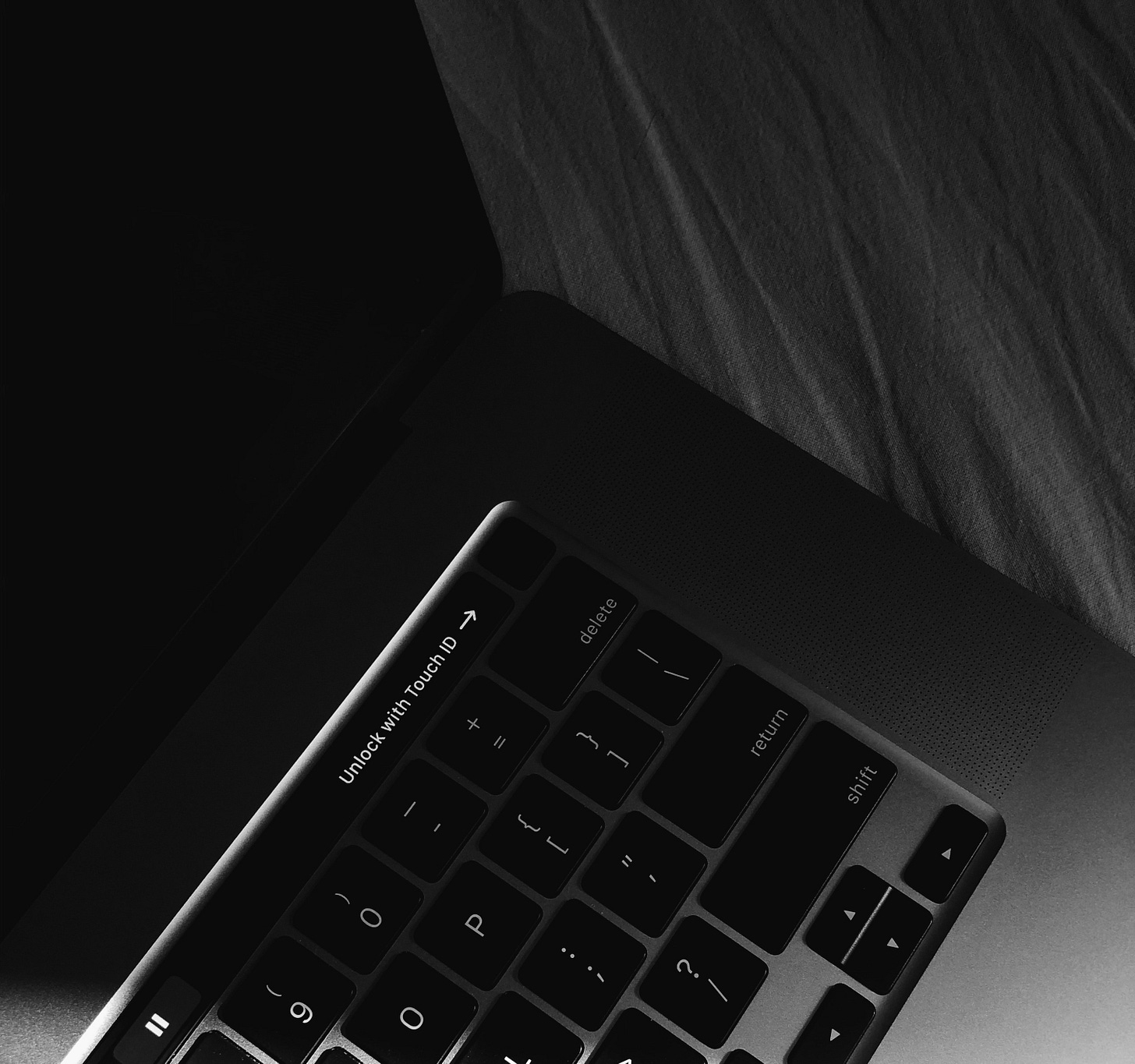 A close-up photo of a computer keyboard that says, "Unlock with Touch ID" with an arrow pointing to a fingerprint sensor. A close-up photo of a computer keyboard that says, "Unlock with Touch ID" with an arrow pointing to a fingerprint sensor.
