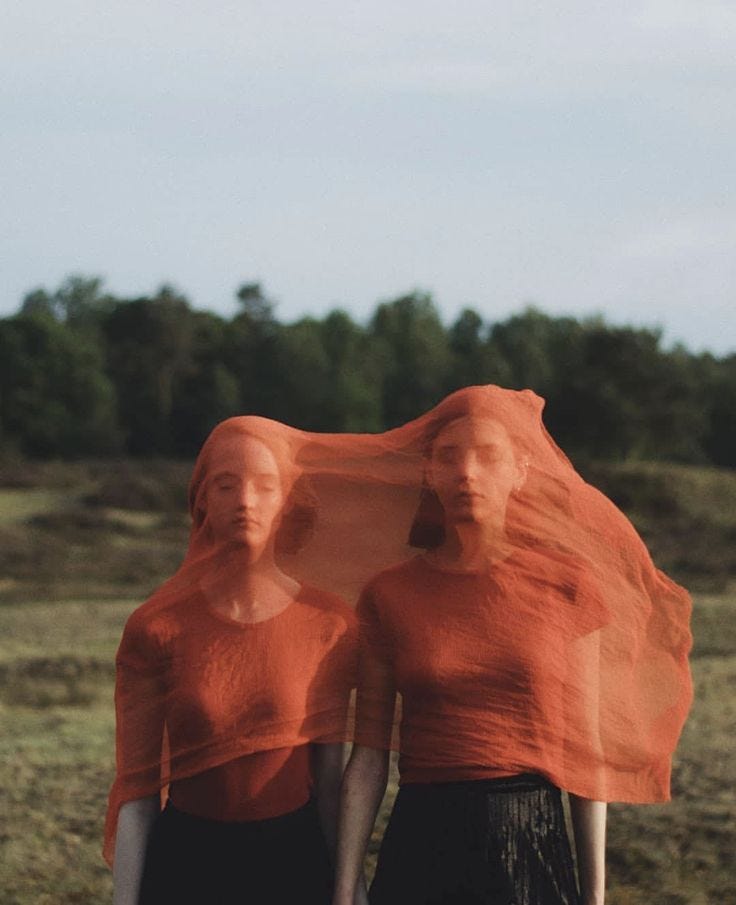 This may contain: two women with orange veils on their heads are walking through the grass in an open field
