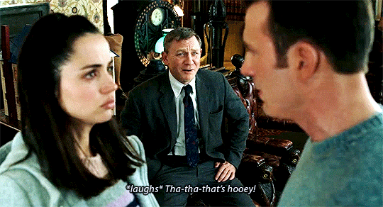Three people, one man and woman in foreground, one man in background speaking, captioned "*laughs* Tha-tha-that's hooey!", source Knives Out (2019) via stedebonny.tumblr.com
