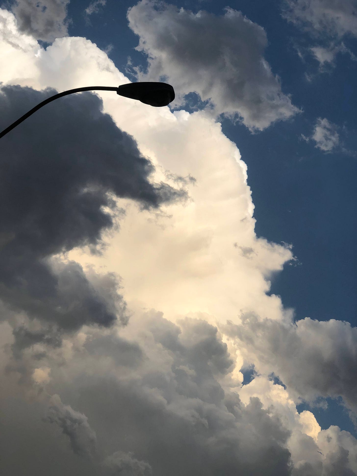 a photo of two clouds: a gray one in the foreground and a white one in the background. they overlap so the white cloud is centered and the gray one further to the left of the image.